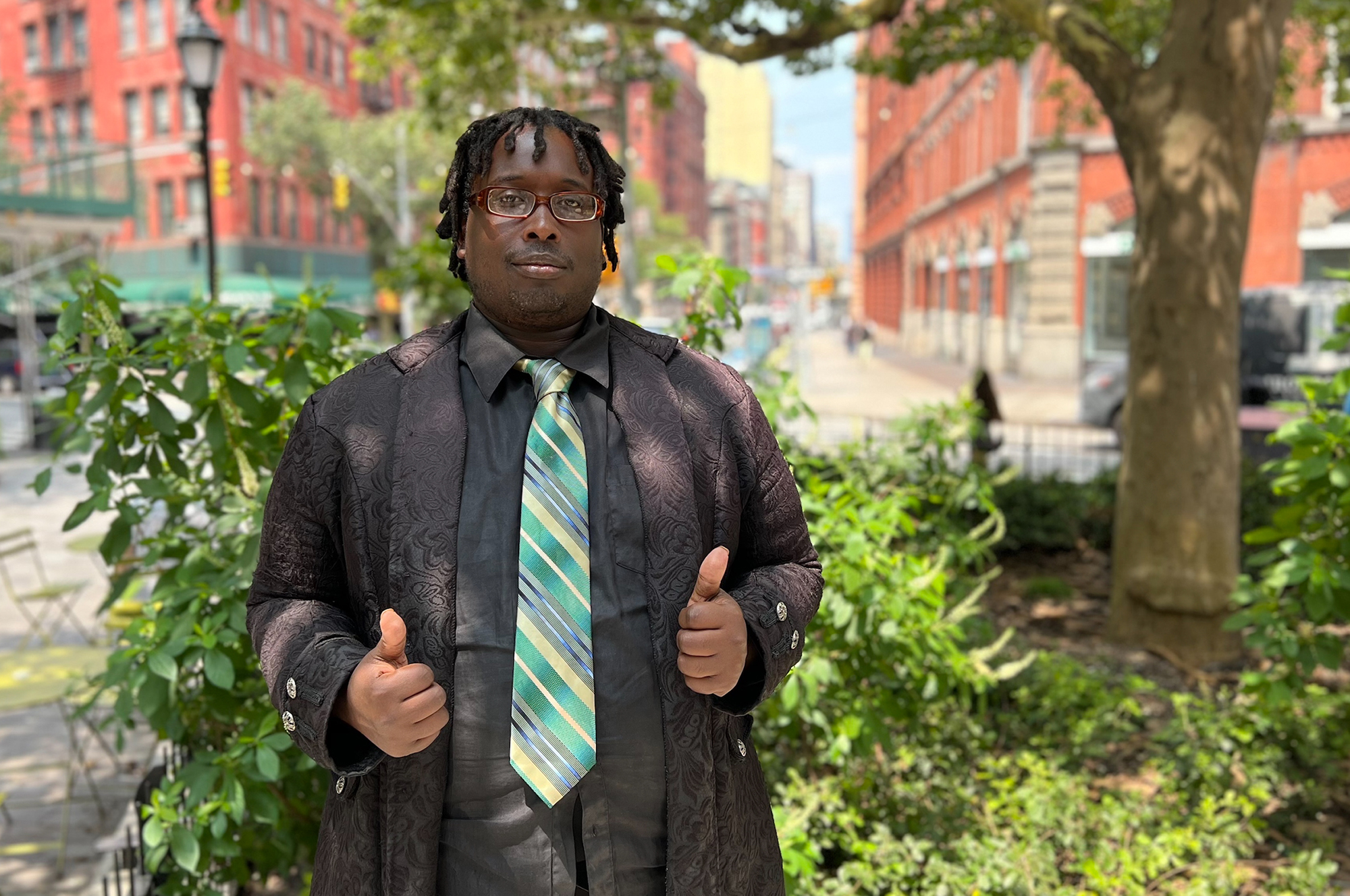 Ryan Ford gives two thumbs up as he stands in a colorful city park